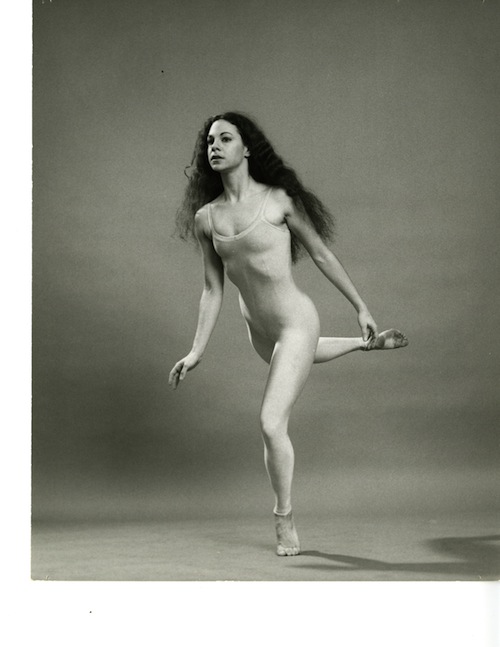 Carla Maxwell with her hair dwn in shimmery unitard perched on the ball of a foot as if she is floating in the air